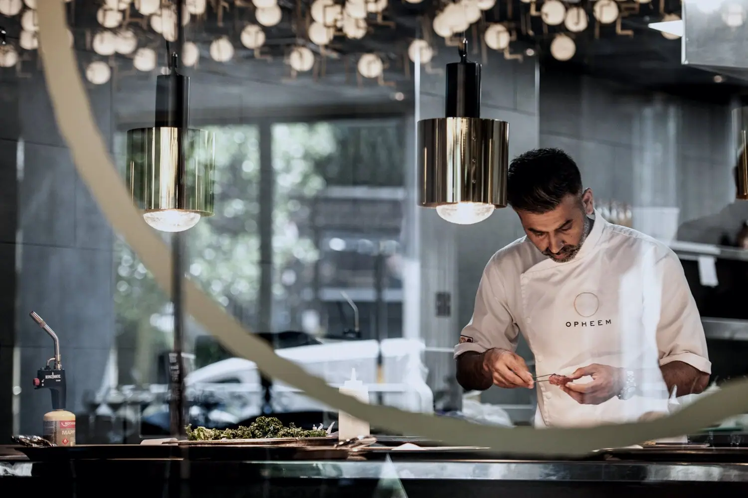 Aktar Islam at the pass, seen through the brass ring, under the dining room lights