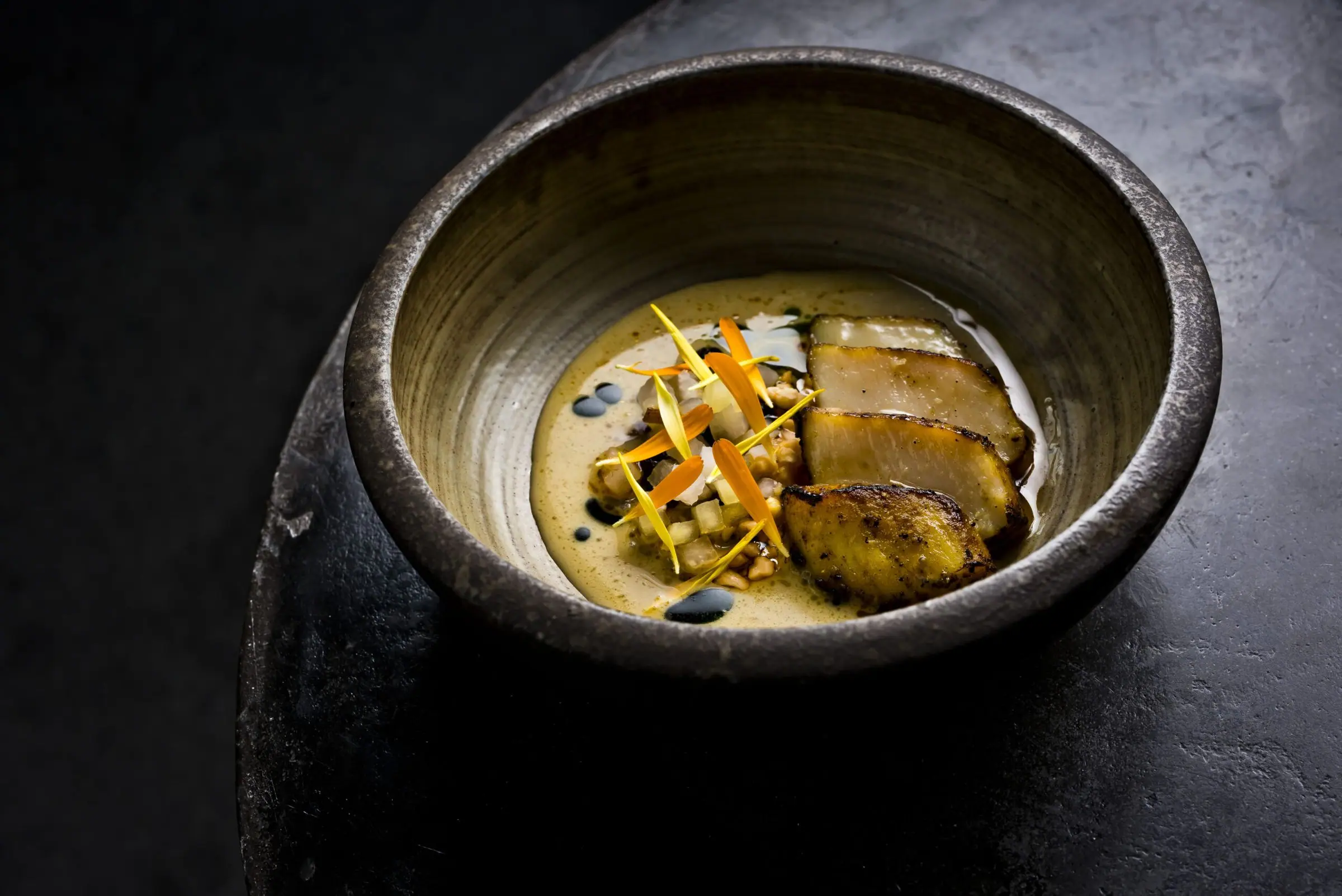 A stoneware bowl of golden broth