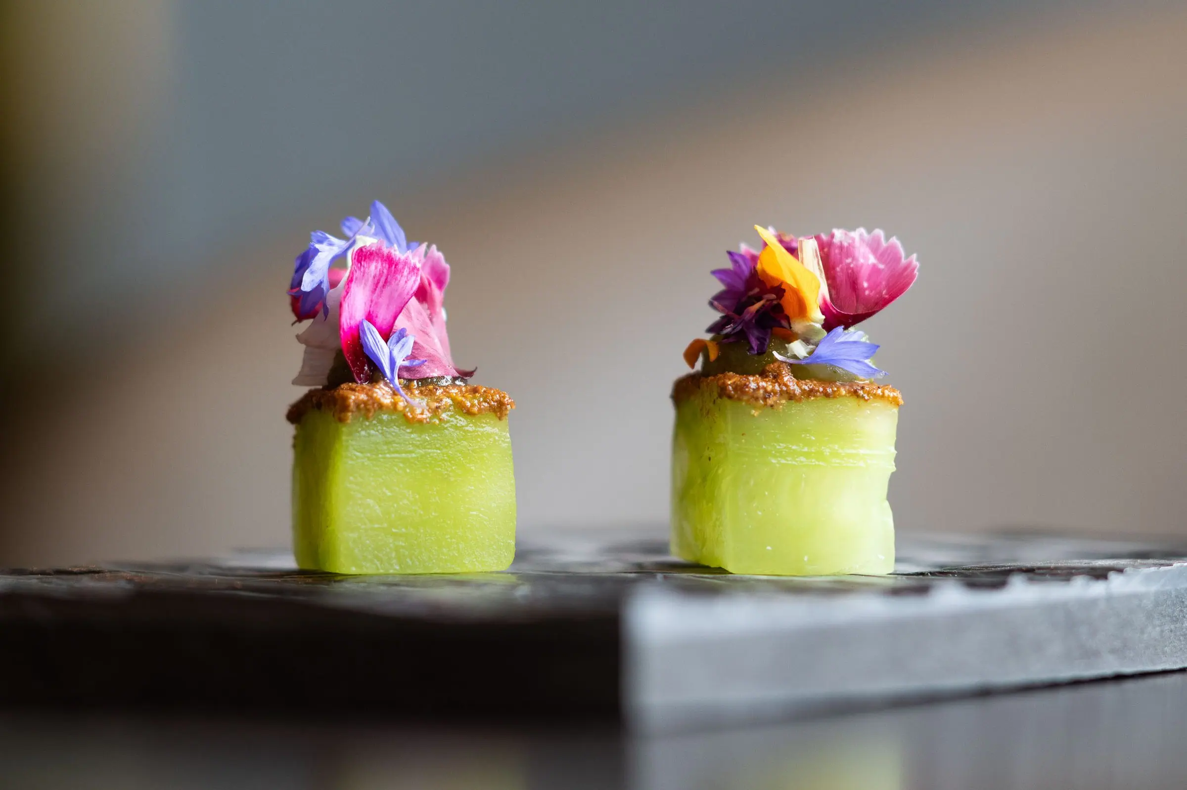 Two cucumber canapés crowned with edible flowers