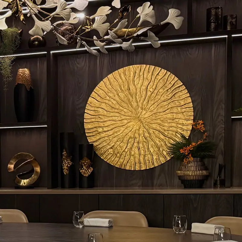 A gold sun sculpture on the wood panelled wall